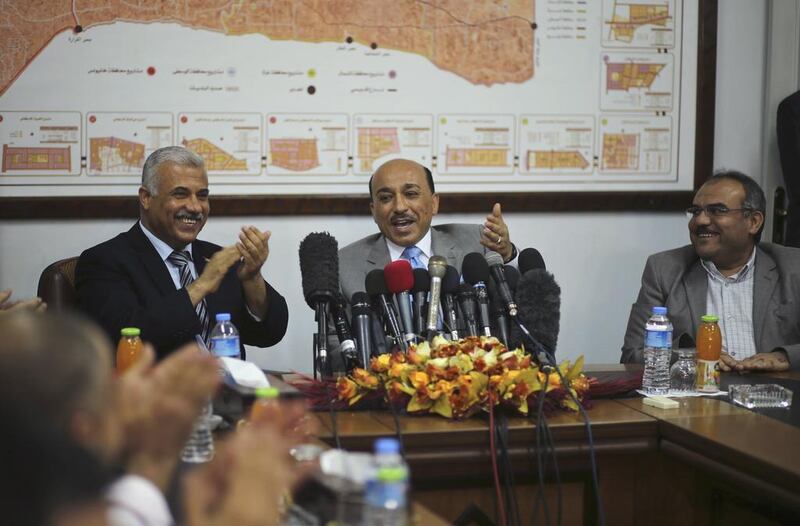 Mufeed Al-Hassayna, the Palestinian minister of housing and public works, centre, gestures as he sits next to former Hamas government minister of housing Youssef Graze, left, during an office handover ceremony in Gaza City on Wednesday. Mohammed Salem / Reuters