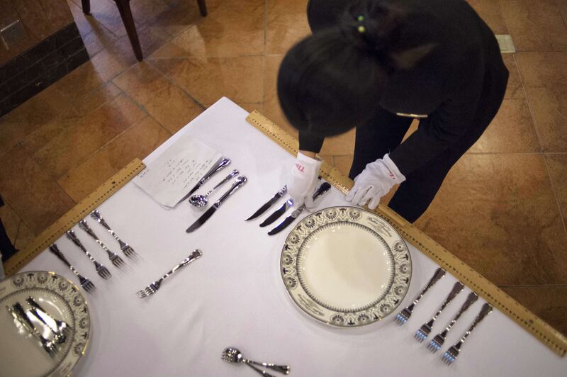 A butler makes sure the table is layed out correctly.