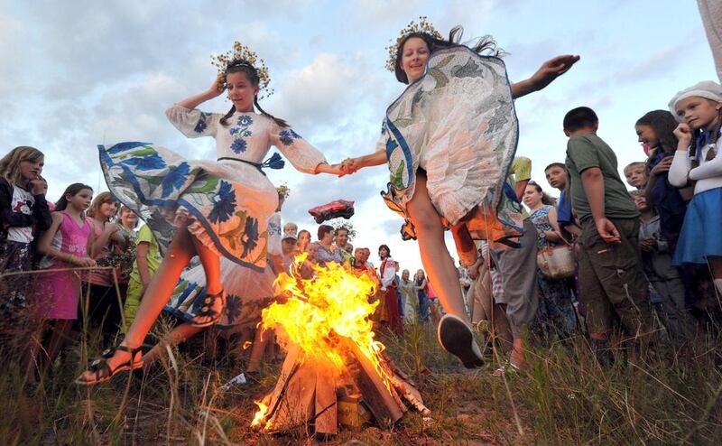 Wearing traditional Belarus costumes girls jump over a bonfire as they celebrate the Ivan Kupala night, an ancient heathen holiday, held in the countryside near the town of Turov, some 260 km southwest of the capital Minsk, on July 6, 2014. People celebrate Kupala Night with bonfires that last throughout the night with some leaping over the flames as it is believed that the act of jumping over the bonfire cleanses people of illness and bad luck.  AFP 