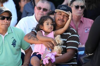 Wilson Garcia holds a young girl during a vigil on Sunday for his son, Daniel Enrique Laso, who was killed alongside Mr Garcia's wife on Friday night. AP