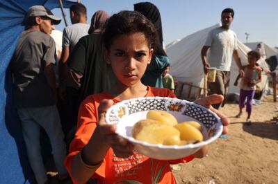 A displaced Palestinian girl shows her plate of food collected at a food distribution point as she and her family shelter in tents set up in a UN-run centre, in Khan Younis, in southern Gaza, on October 26. AFP