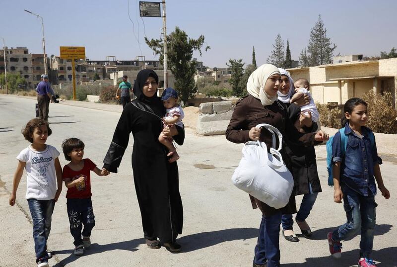 Women and their children leave the Moadamiyeh suburb of Damascus on September 2, 2016, following a deal struck with the government. AP Photo