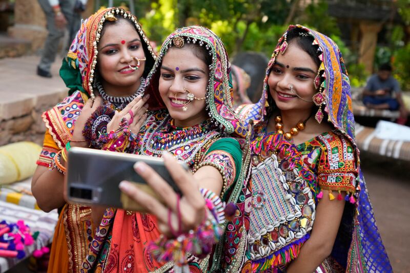 Women in colourful traditional attire take a selfie as they practice the garba. AP