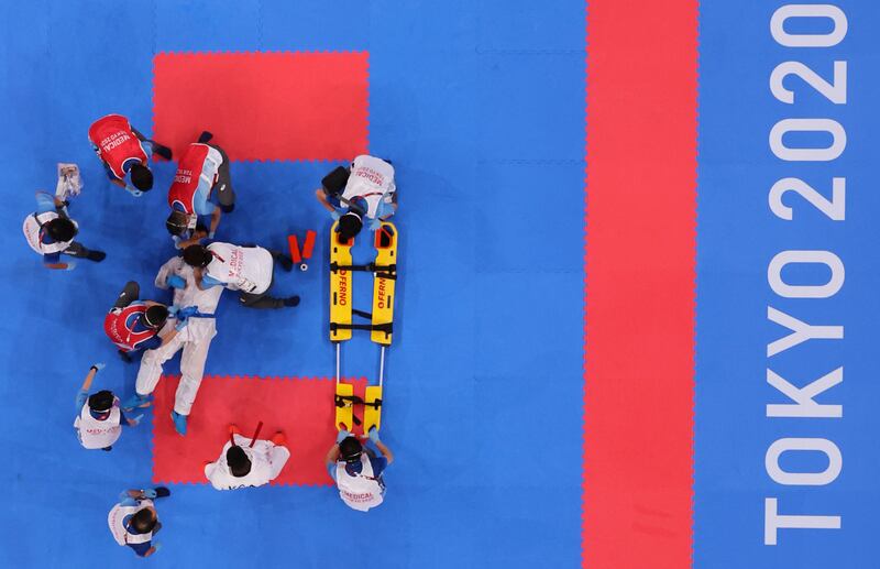 Medical personnel prepare to move Sajad Ganjzadeh of Iran onto a stretcher during his match against Tareg Hamedi of Saudi Arabia in the men's +75kg Kumite Olympic Games final at Nippon Budokan in Tokyo.