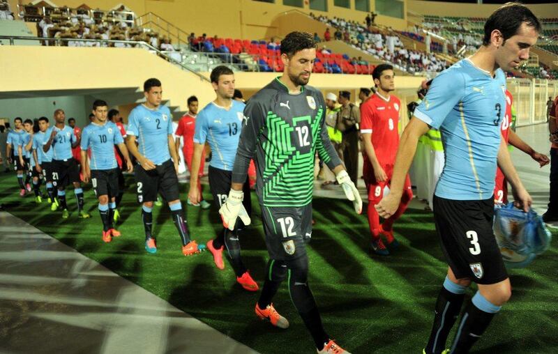 The Uruguay national football team, in blue, walks out with the Oman national football team, in red, before a friendly in Al Buraimi, Oman on Monday. Hamid Al Qasmi / EPA / October 13, 2014