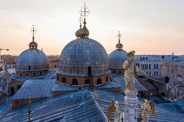 An aerial view taken on April 25, 2020 shows a sculpture of Venice's patron apostle St. Mark with angels (R) atop St. Mark's Basilica as the sun rises over Venice, during the country's lockdown aimed at curbing the spread of the COVID-19 infection, caused by the novel coronavirus. (Photo by MARCO SABADIN / AFP)
