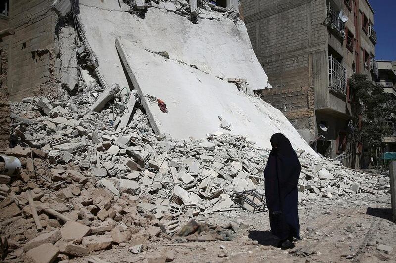 A woman walks past a damaged building after an airstrike in the rebel held Douma neighbourhood of Damascus, Syria. Bassam Khabieh / Reuters