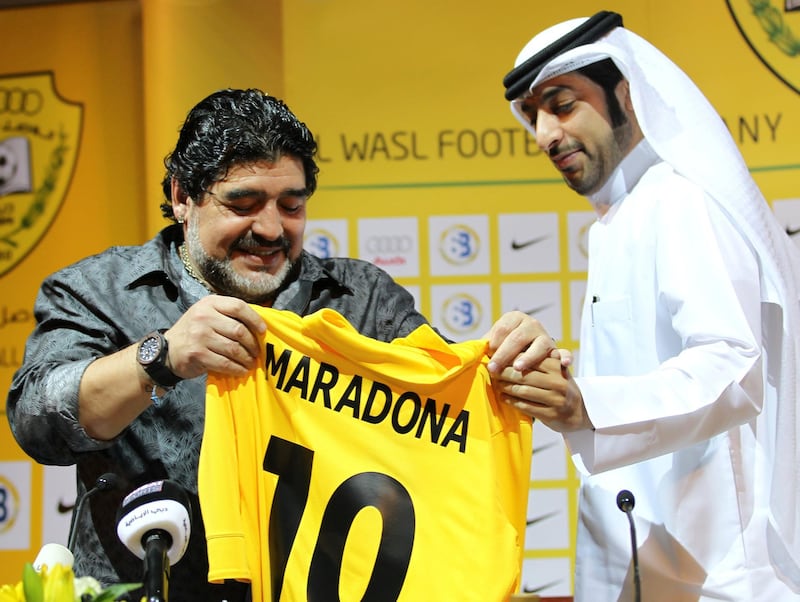Argentine football legend Diego Maradona (L) looks at his new shirt with Marwan Bin Bayat, chairman of the Emirati al-Wasl Football Company, during a press conference in Dubai, on September 11, 2011. AFP PHOTO/Karim SAHIB (Photo by KARIM SAHIB / AFP)