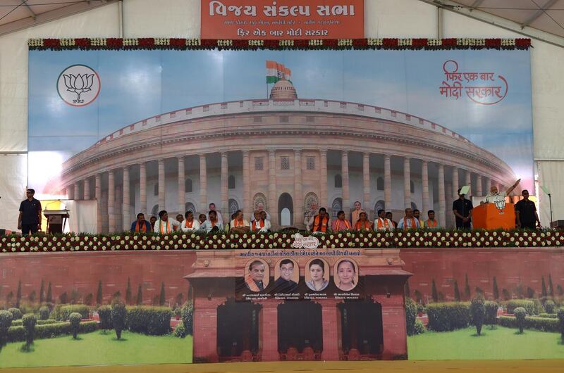 Indian Prime Minister Narendra Modi (2nd R) gives a speech on a stage with the backdrop of the Indian Parliament Building at a rally in Amreli, some 250km from Ahmedabad, on April 18, 2019. More than 157 million of the 900 million electorate are eligible to cast ballots on the second of seven days of voting in the world's biggest election. / AFP / SAM PANTHAKY
