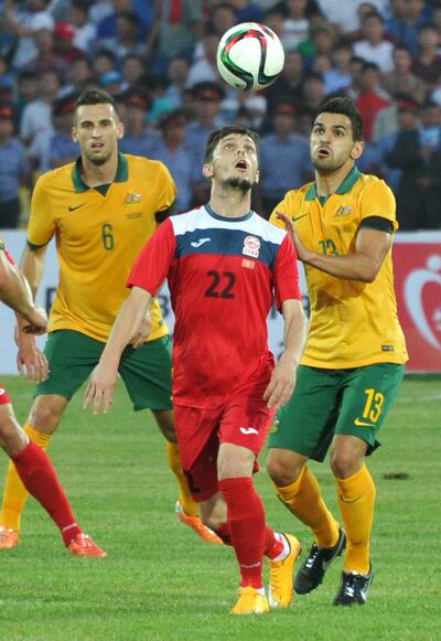 Kyrgyzstan's Anton Zemlianukhin (C) vies for the ball with Australia's Aziz Behich (R) during the FIFA World Cup 2018 Group B qualifying football match between Kyrgyzstan and Australia in Bishkek on June 16, 2015. AFP PHOTO / VYACHESLAV OSELEDKO (Photo by VYACHESLAV OSELEDKO / AFP)