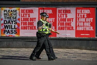 Two police officers walk past posters in Glasgow, during the coronavirus lockdown that is projected to shrink the UK's economy by 30% in the first half of the year and 14% overall in 2020. Payments data indicates spending by UK households dropped 30% in March and April, according to the Bank of England. Getty Images