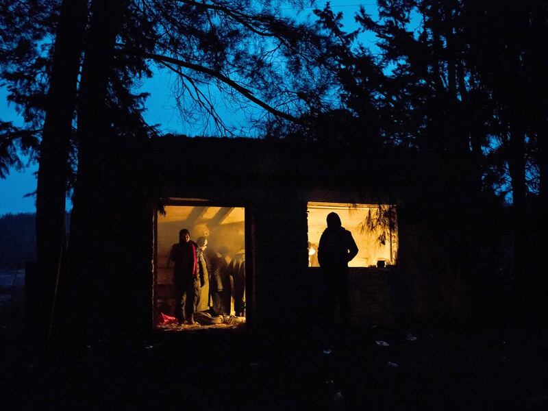 Refugees huddle around a fire in a building in a forest near the Macedonia border. They will try to enter the country before moving to Europe. Lazar Simeonov for The National