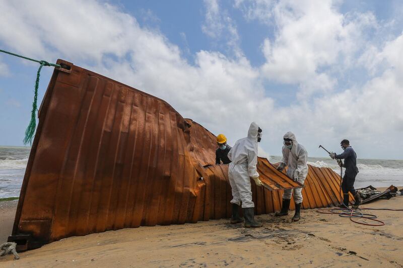 Sri Lankan Navy soldiers remove containers from cargo vessel 'MV X-Press Pearl', washed ashore off the coast of Colombo, Sri Lanka. The ship was damaged when chemicals exploded, starting a fire. EPA