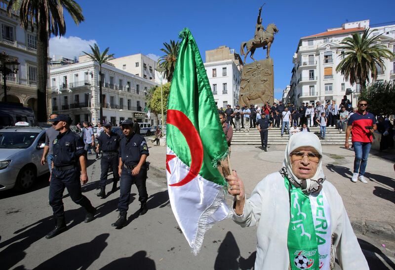 A demonstrator carries a national flag near police officers during a protest opposing the election that Algeria's veteran ruling cadre has set for December and demanding the freeing of opposition leaders in Algiers. Reuters