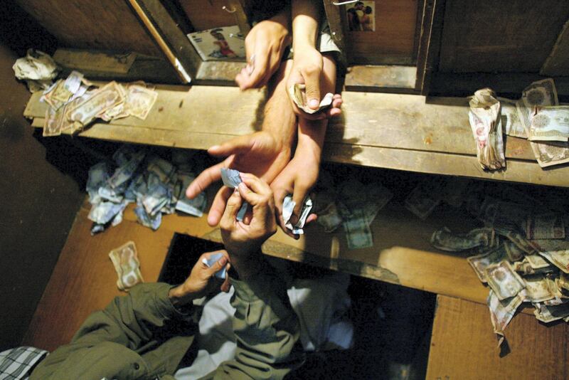 KABUL,  AFGHANISTAN - OCTOBER 14:  Afghan men shove their money through a small window to buy tickets for a movie at he Park Cinema October14,2002 in Kabul, Afghanistan. Tickets cost around 10 cents (8,000 Afghani). Only men are allowed to go and see the popular Indian Bollywood films.  (Photo by Paula Bronstein/Getty Images)