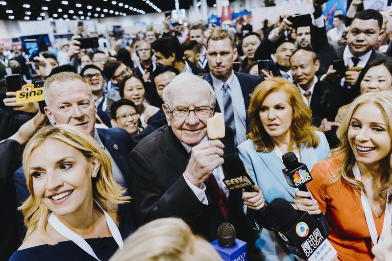 Warren Buffett, chairman and chief executive officer of Berkshire Hathaway Inc., center left, eats a Dairy Queen vanilla orange ice cream bar while touring the shopping floor ahead of the company's annual meeting in Omaha, Nebraska, U.S., on Saturday, May 4, 2019. Buffett's Berkshire Hathaway agreed earlier this week to make the investment in Occidental to help the oil producer with its $38 billion bid for Anadarko Petroleum Corp. Photographer: Houston Cofield/Bloomberg