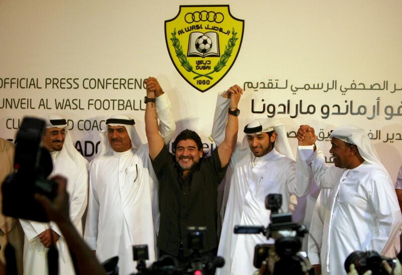Argentine football legend Diego Maradona (C) gestures with officials of the United Arab Emirates al-Wasel football club following a press conference in Dubai, June 04, 2011. Maradona was introduced as the new coach of the al-Wasel club for the next two years.       AFP PHOTO/MARWAN NAAMANI (Photo by MARWAN NAAMANI / AFP)