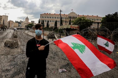 A protester waves a Lebanese flag alongside a barbed wave set up to protect the government palace in downtown Beirut. Lebanese Prime Minister Saad Hariri announced a series of economic measures adopted by the government and approved the 2020 budget without any new taxes.EPA