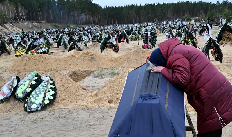 A woman weeps next to her husband's coffin at a cemetery in Irpin. AFP