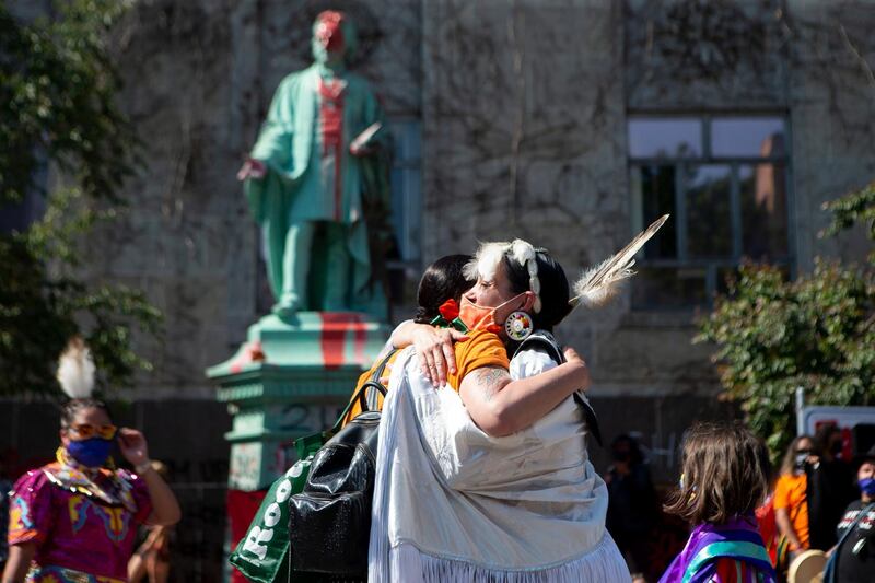 Two women embrace in front of Egerton Ryerson statue as they honor the lives of the 215 children found buried at the former Kamloops Indian Residential School during a Bring Our Children Home March in Toronto on Sunday, June 6, 2021. Ryerson was the chief superintendent of education for Upper Canada and his recommendations were regarded as instrumental in the design and implementation of the Indian Residential School System. (Chris Young/The Canadian Press via AP)