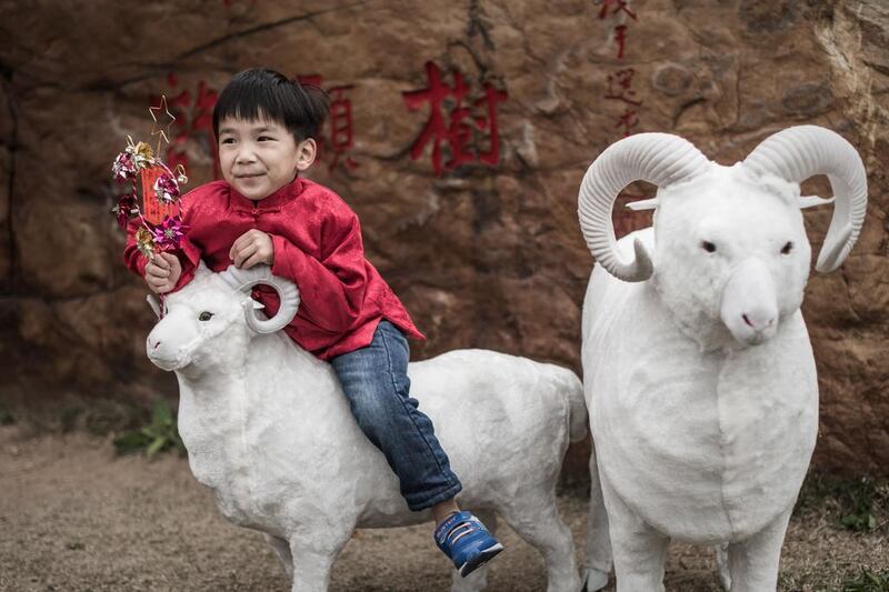 A boy stands on a model of a ram near a temple during celebrations to mark the first day of the Lunar New Year in Hong Kong on February 19, 2015. Philippe Lopez / AFP

