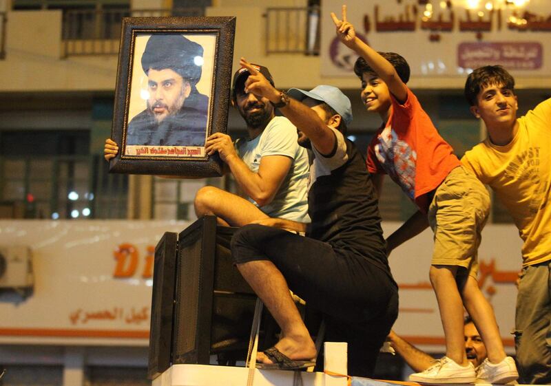 An Iraqi man celebrates with a picture of Shiite cleric Muqtada Sadr during the general election in Baghdad on May 14, 2018.  The race to become Iraq's next prime minister appeared wide open as two outsider alliances looked to be in the lead after the first elections since the defeat of the Islamic State group. / AFP / AHMAD AL-RUBAYE
