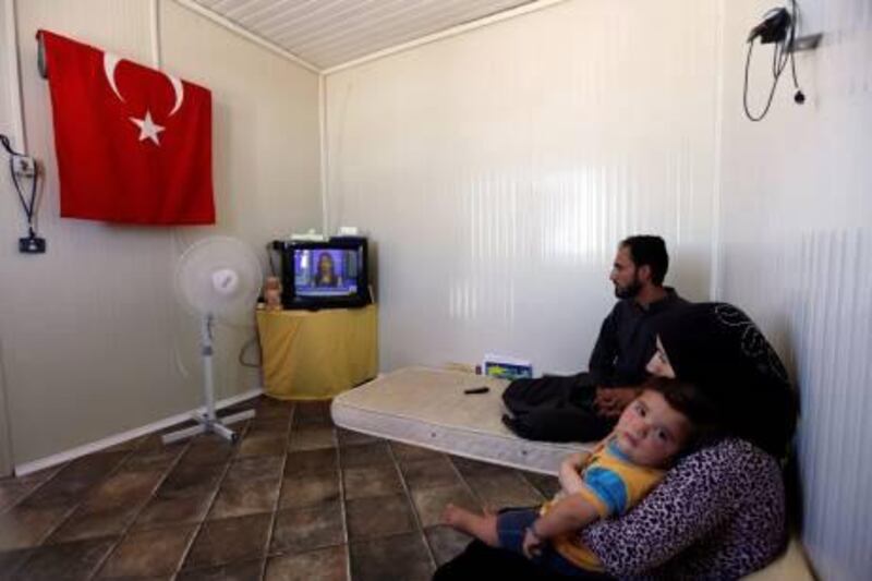 A Syrian refugee family watches television at a refugee camp named "Container City" on the Turkish-Syrian border in Oncupinar in Kilis province, southern Turkey July 3, 2012.  REUTERS/Osman Orsal (TURKEY - Tags: POLITICS SOCIETY IMMIGRATION) *** Local Caption ***  OSM10_TURKEY-_0703_11.JPG