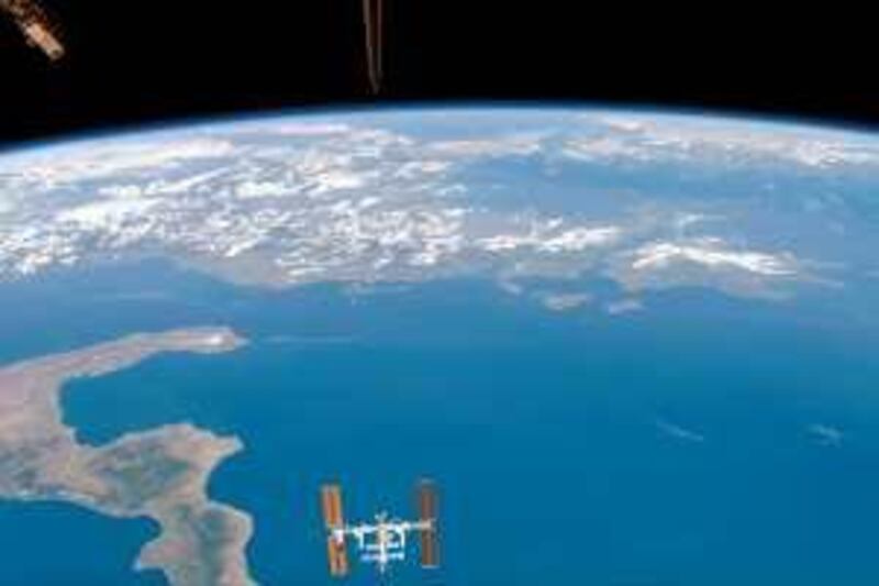 This photo provided by NASA shows, backdropped by Earth's horizon and the blackness of space, the international space station appearing to be very small, as the space shuttle Endeavour pulls away from it, Sunday Aug. 19, 2007. Undocking of the two spacecraft occurred at 6:56 a.m. Sunday. The lower portion of Italy is visible at left. (AP Photo/NASA)
