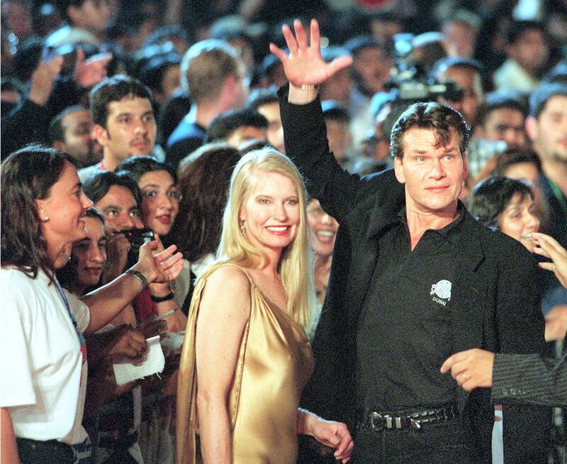 American actor Patrick Swayze waves to the crowd gathered for the opening of the new Planet Hollywood restaurant in Dubai 26 May. The star-owned restaurant made its debut in the Arab world with a rock-and-roll performance featuring US actor Bruce WIllis. (Woman next to Swayze is unidentified) (Photo by RABIH MOGHRABI / AFP)