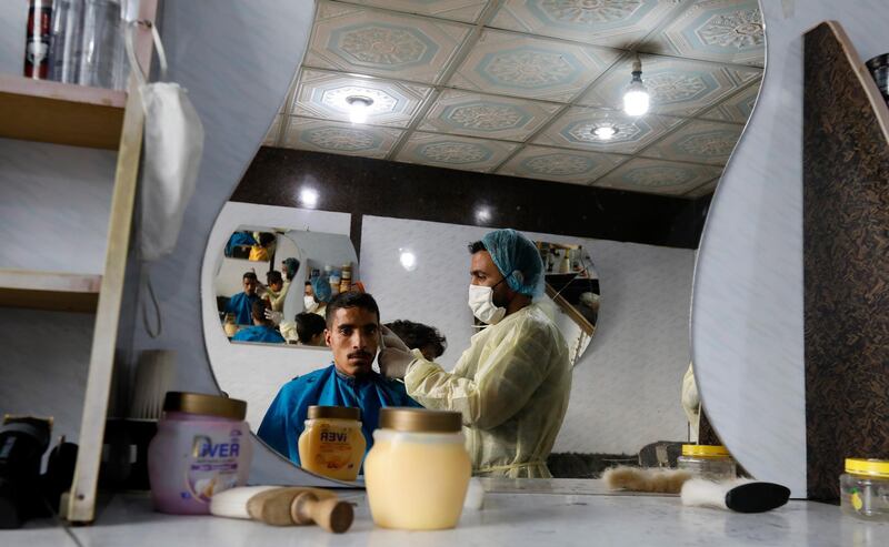 A hairdresser wearing a protective suit gives customer a haircut  in Sanaa, Yemen.  EPA