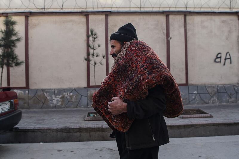 A man carries a rug in Kabul. Rug hunters can spend weeks collecting a diverse selection of pieces that they can later sell. AFP