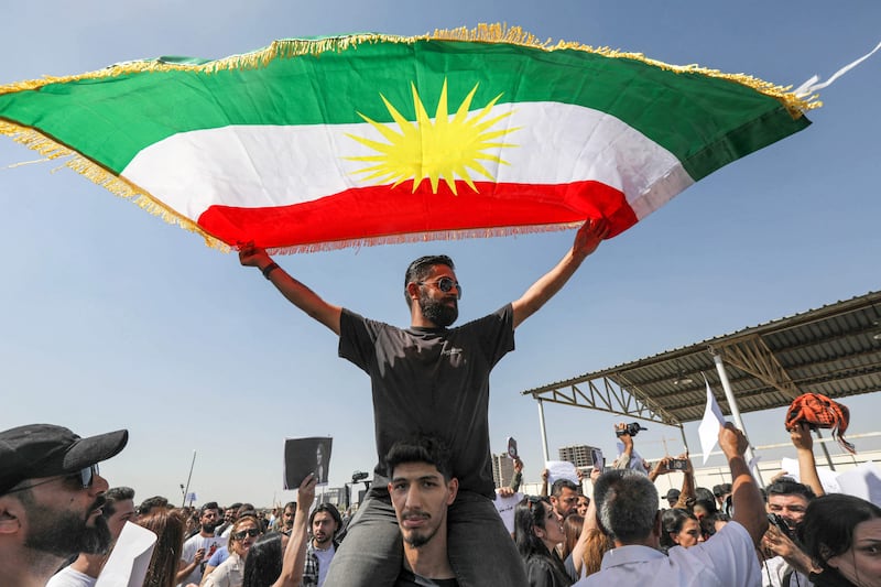 A man waves a Kurdish flag as he sits upon the shoulders of another during a demonstration against Iran in Erbil, the capital of Iraq's autonomous Kurdistan region. AFP