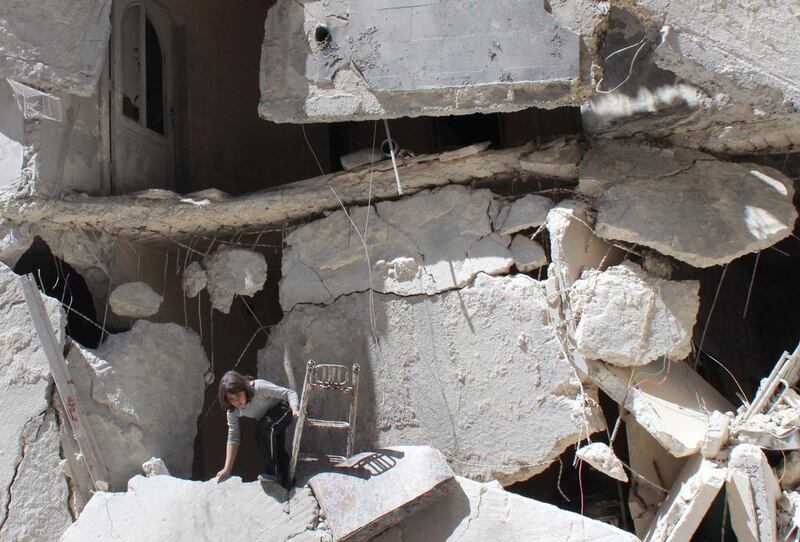 A Syrian girl collects her belongings from rubble after her building was reportedly destroyed in an air raid by government forces in the northern city of Aleppo. Baraa Al-Halabi / AFP  