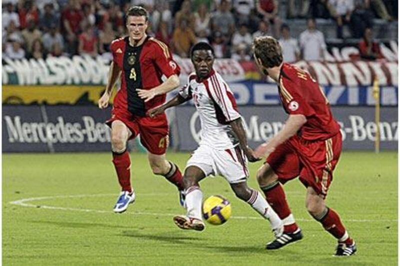 The UAE striker Ismail al Hammadi, flanked by Germany's Robert Huth, left, and Andreas Hinkel shapes to shoot during his side's friendly defeat.