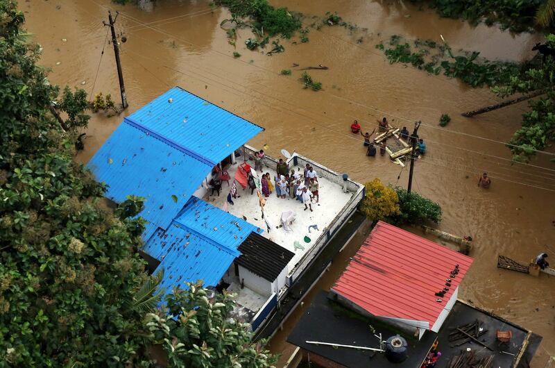 People wait for aid on the roof of their house in Kerala, India. Reuters