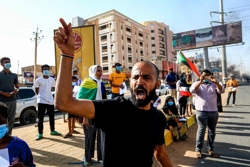 Sudanese protesters, some clad in masks as a precaution due to the coronavirus pandemic, chant slogans as they gather to mark the first anniversary of a raid on an anti-government sit-in, in the Riyadh district in the east of the capital Khartoum.  AFP