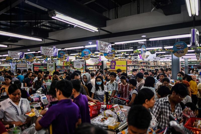 This photo taken on March 12, 2020 shows people panic buying groceries in a supermarket, after hearing rumours related to the COVID-19 coronavirus, in Yangon. Shelves are being stripped bare of toilet rolls, hand sanitiser and surgical masks everywhere from Japan to France to the United States as panic buying criss-crosses the globe with the coronavirus, defying repeated calls for calm and disrupting supply chains. / AFP / Ye Aung THU
