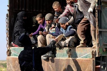 A fighter from the Syrian Democratic Forces (SDF) gives bread to children near the village of Baghouz. Reuters 