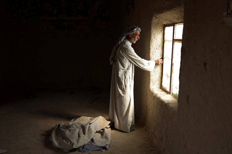 Taha Yassin, 46, stands inside the deserted home of his neighbour, Hedyya Ouda who's family have left the village of Al-Bouzayyat, in Diwaniya, Iraq, November 8, 2022.  "The village is empty," said Hedyya Ouda, one of the few remaining residents when Reuters visited her in October.  Hedyya and her husband stopped growing wheat and barley three years ago because of water shortages, sold their livestock and were forced to travel about 60 km (40 miles) twice a month to buy drinking water.  When Reuters returned to their village in November, both had left for the city.    REUTERS/Alaa Al-Marjani    SEARCH "CLIMATE MIDEAST WATER" FOR THIS STORY.  SEARCH "WIDER IMAGE" FOR ALL STORIES. 