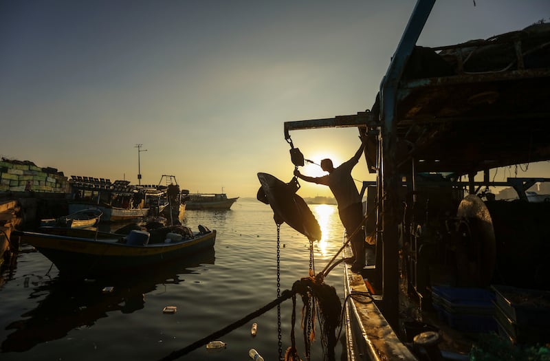 Palestinian fishermen arrive back from a fishing trip at the port of Gaza City on  27 June 2018.For hours every morning the fishermen wade through the surf on the beach or paddle a few hundred yards off the coast casting their small nets to bring back food for their families. The fishermen agree that there are less and less fish to be caught off the beach because raw sewage being dumped into the ocean is driving the fish further out to sea. By Wissam Nassar.
