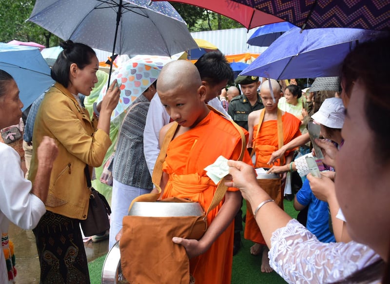 Novice monk Ekarat 'Bew' Wongsukchan, centre, and Duganpet 'Dom' Promtep, receive offerings after their participation in a Buddhist novice monk ordination ceremony. EPA