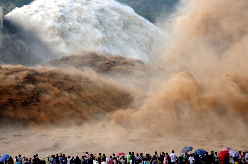 Tourists look at effects of water and sediment regulation at Xiaolangdi Dam on July 5, 2014 in Zhengzhou, Henan province of China. Large volumes of mudflow and the clear water flow combine together just like two dragons dance at Xiaolangdi Dam which has attracted a lot of visiters. Getty Images