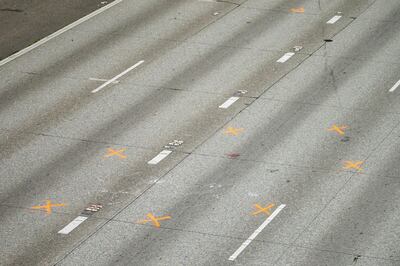 Two women were struck and critically injured where orange evidence markers are seen when a car sped through their small protest gathered on a closed Interstate 5 near the Yale Avenue on-ramp in Seattle, early Saturday July 4, 2020. Authorities say a 27-year-old man suspected of driving onto the closed freeway in Seattle early Saturday and barreling into a crowd of protesters has been arrested and booked on two counts of vehicular assault. (Bettina Hansen/The Seattle Times via AP)