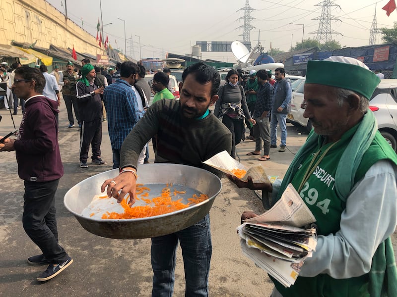 A man distributes sweets to celebrate news of the repeal of farm laws they were protesting against, in Ghazipur, on the outskirts of New Delhi on November 19, 2021. AP Photo