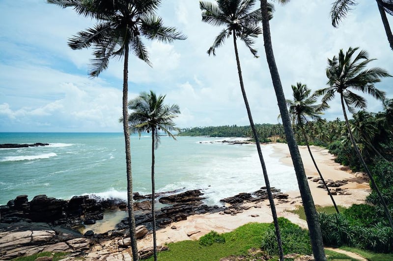 The Anantara Peace Haven Tangalle Resort overlooks a palm tree-framed beach. Courtesy Anantara Hotels, Resorts & Spas