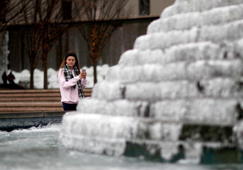 Emme Hillman, visiting from Florida, take a photo of a frozen water fountain in Atlanta, Georgia. David Goldman / AP Photo