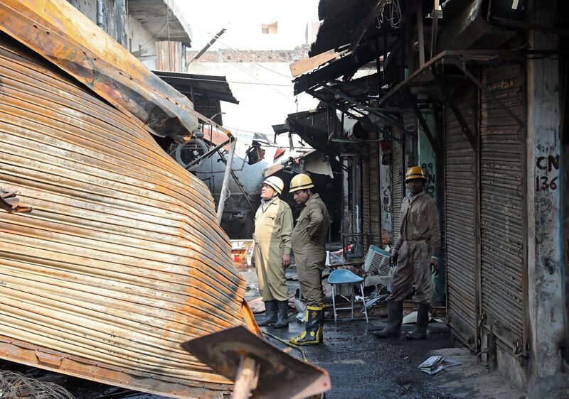 Firefighters looks at debris at a burnt market near Gokulpuri metro station area after clashes in New Delhi, India.  EPA