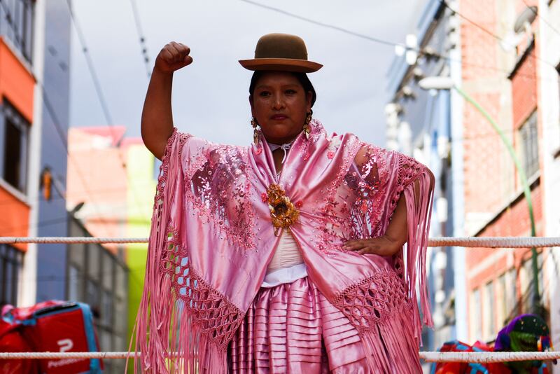 A Cholita wrestler in full costume flexes her bicep. The fighters help tackle gender stereotypes and discrimination against indigenous people. Reuters