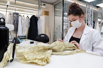 An employee prepares a miniature dress for the recording of Dior Haute Couture collection's presentation movie, in Dior's sewing workshop in Paris, on July 4, 2020. / AFP / FRANCOIS GUILLOT
