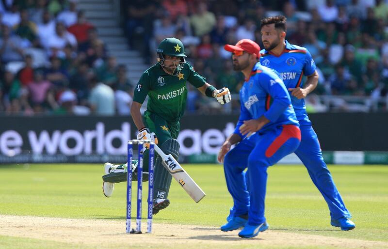 Pakistan's Babar Azam (C) avoids Afghan fielders as he runs between the wickets during the 2019 Cricket World Cup group stage match between Pakistan and Afghanistan at Headingley in Leeds, northern England, on June 29, 2019. (Photo by Lindsey Parnaby / AFP) / RESTRICTED TO EDITORIAL USE